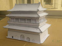 a white model of the bejing drum tower on a brown cardboard box in a veranda